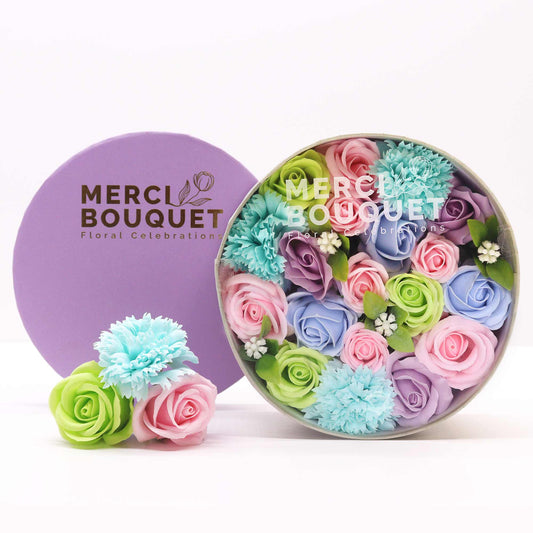 A round gift box full of blue, green, pink and purple soap flowers. Roses. The petals are made of soap.