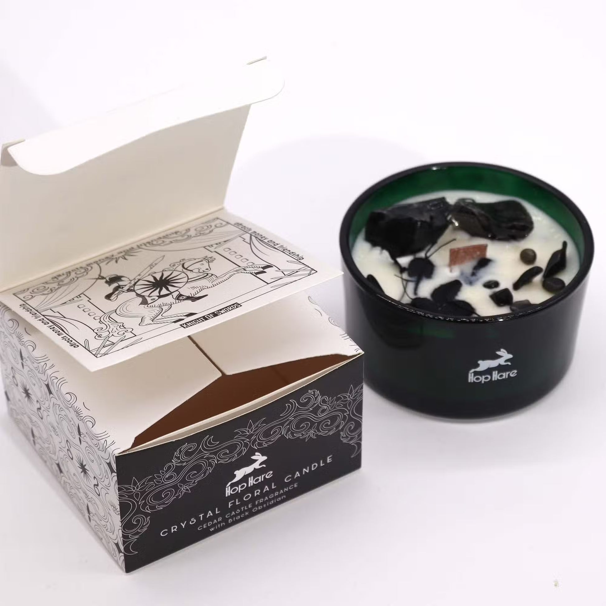 'The Knight of Swords' gift box next to the soy candle with crystals and dried flowers in a green glass jar. 