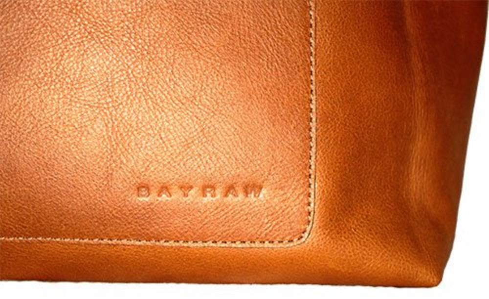 Close-up of stitching and embossed Bayraw name on the front of a brown leather tote bag.