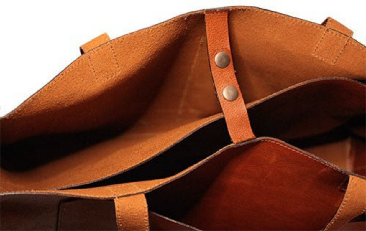 Close-up of a brown leather tote bag by Bayraw. Two handles. A strap to close it.