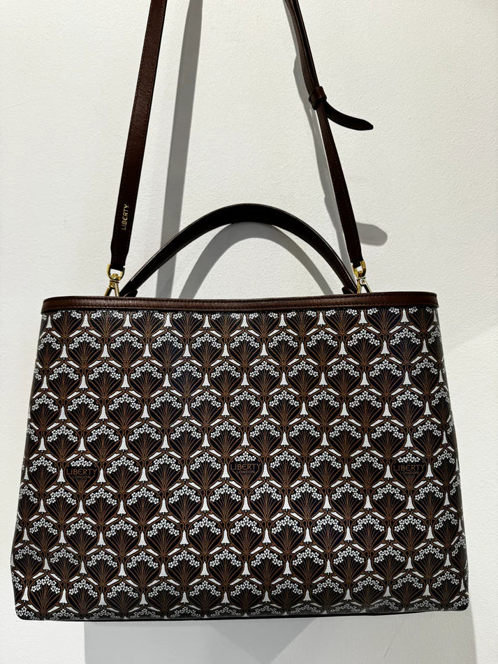 A Liberty Burlington bag on on a wall. A long leather strap and handle.