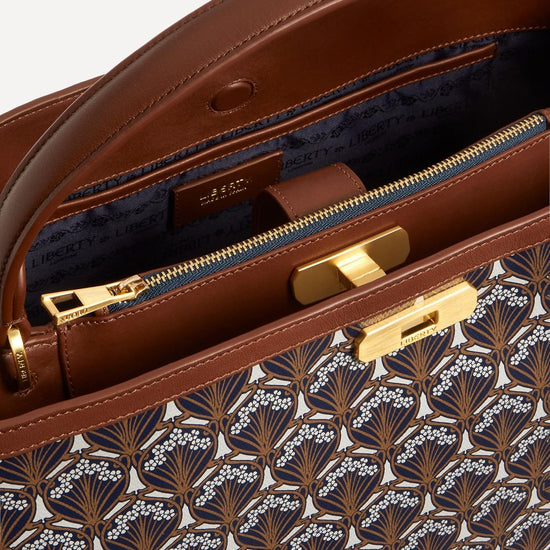 Close up view of the top of the Liberty Burlington top handle bag. Shows pattern zip, lock and handle.