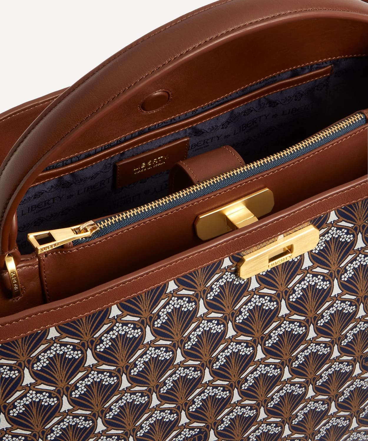 Close up view of the top of the Liberty Burlington top handle bag. Shows pattern zip, lock and handle.