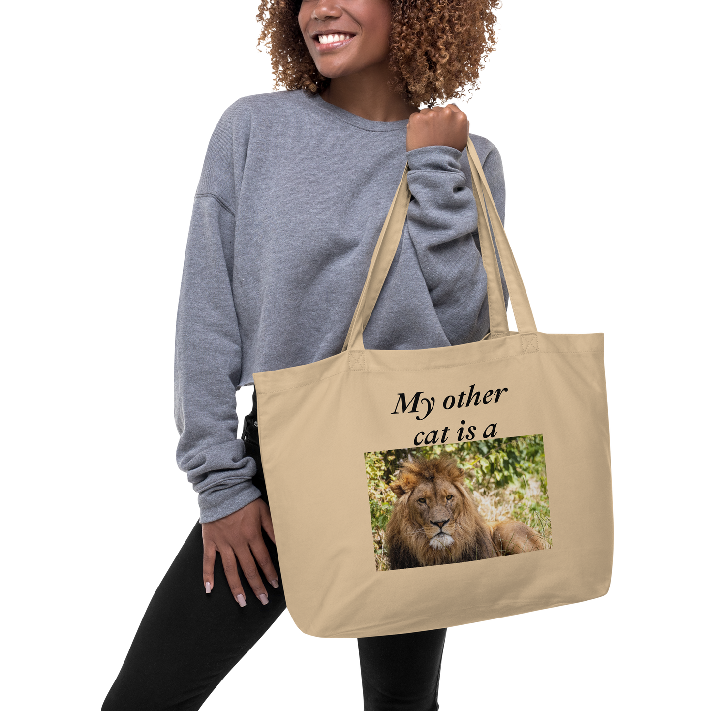 Woman holding a large beige organic cotton tote bag. With a lion image and text: My other cat is