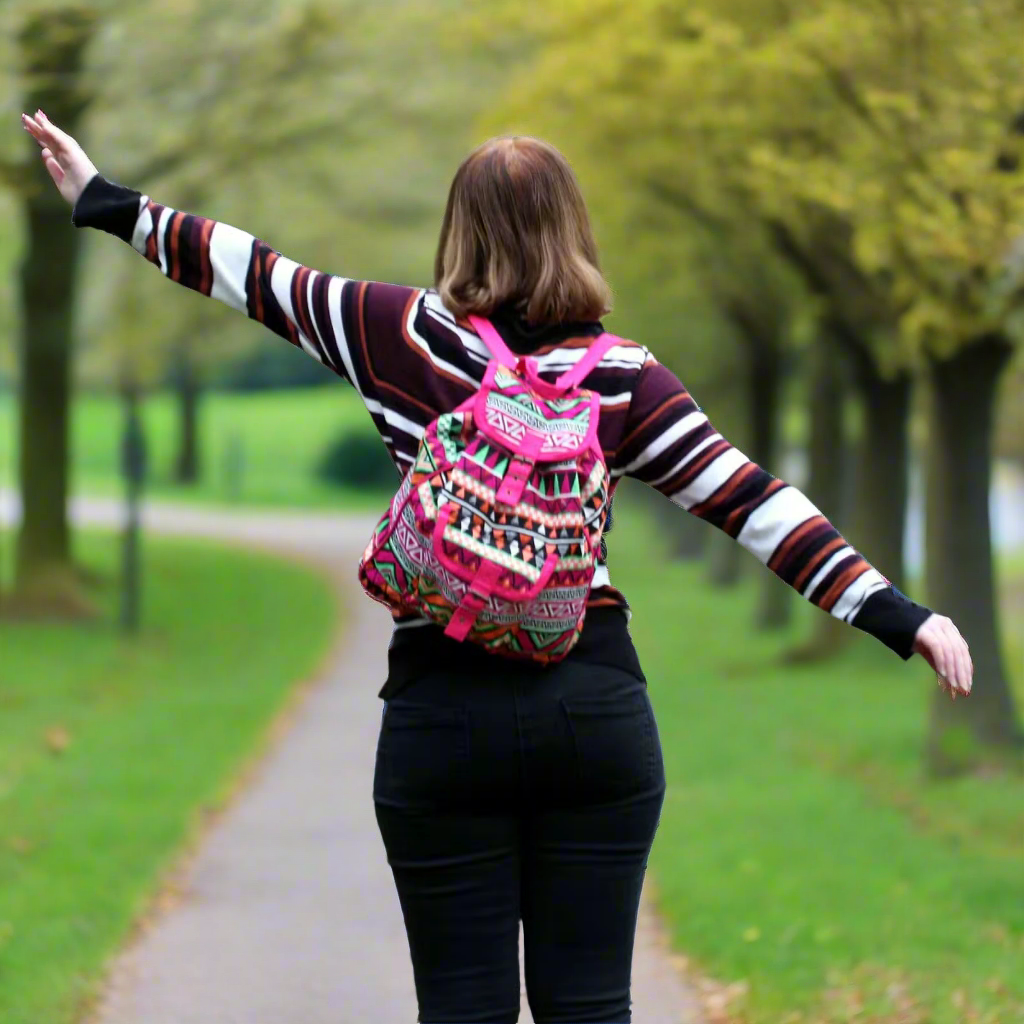 Woman with a multi-colour jaquard backpack walking in a park.
